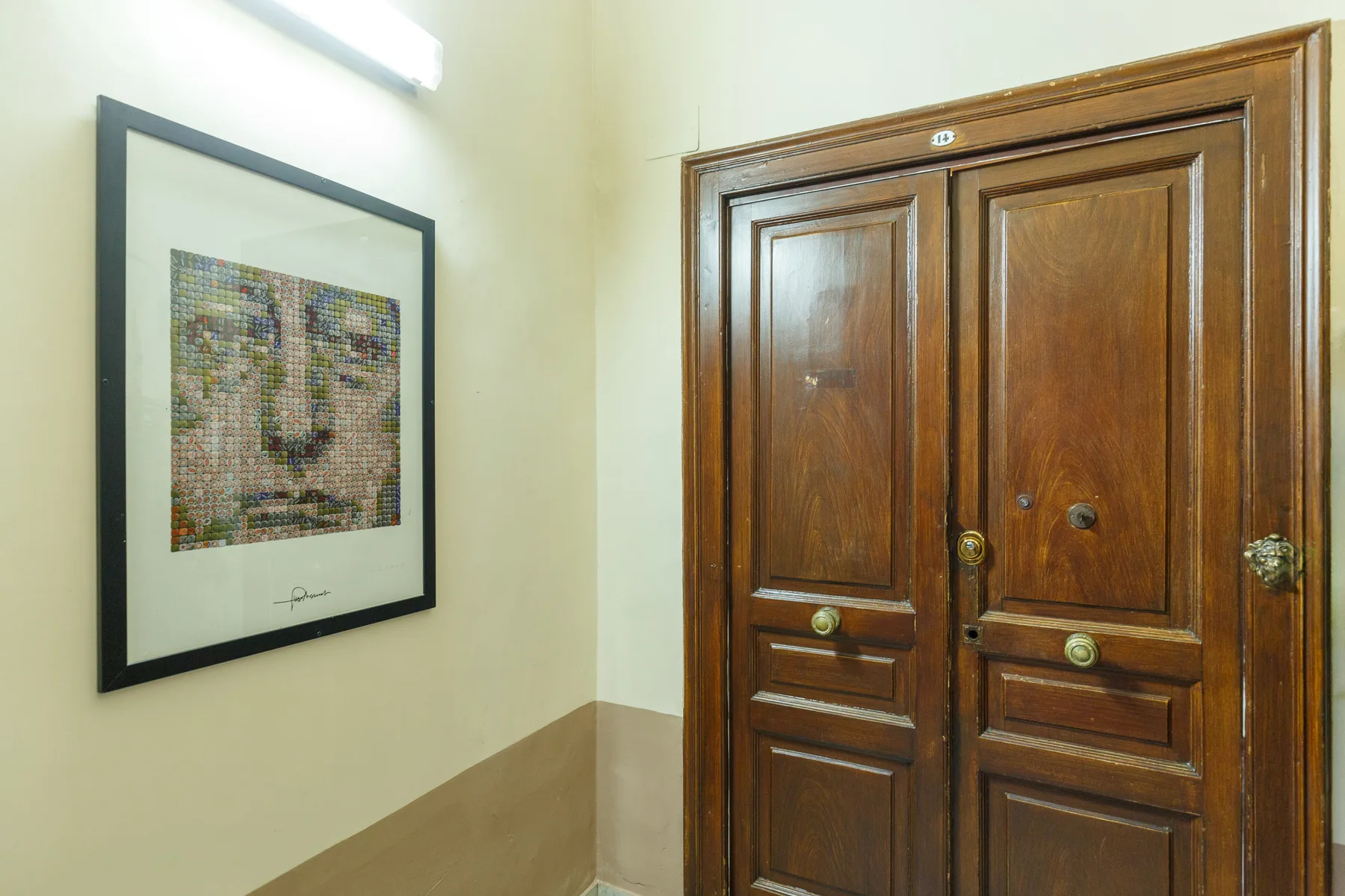Un pasillo con una obra enmarcada junto a una puerta doble de madera.