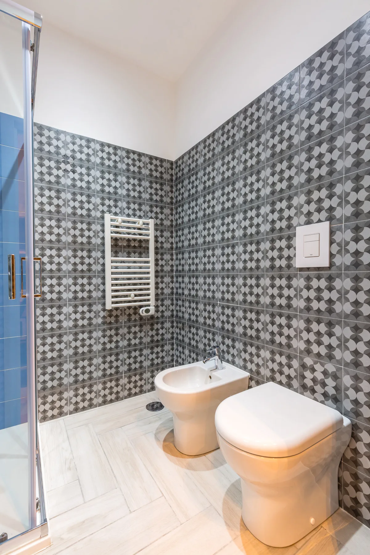 Un baño con paredes de azulejos estampados, un inodoro y un bidé.