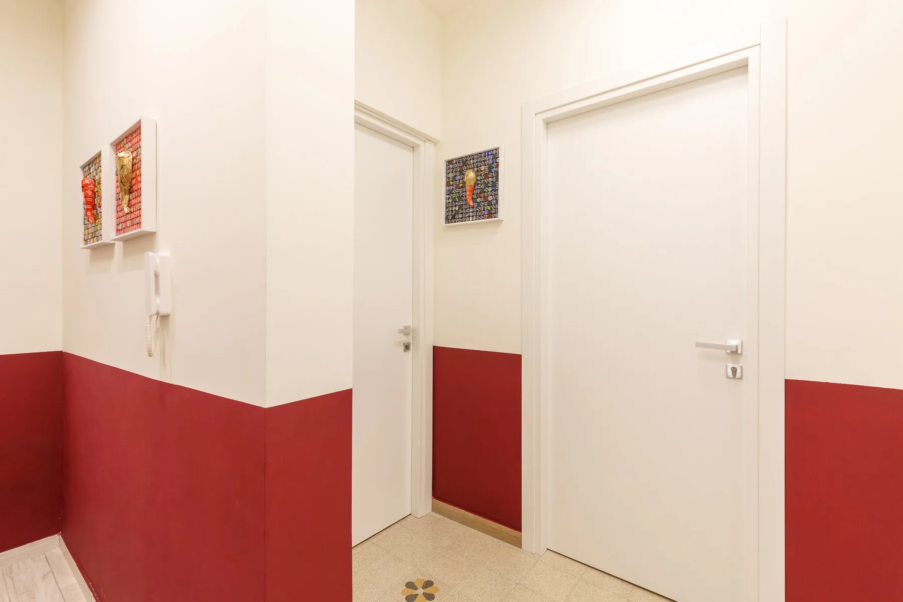 Un pasillo con puertas blancas y paredes rojas en la parte inferior.