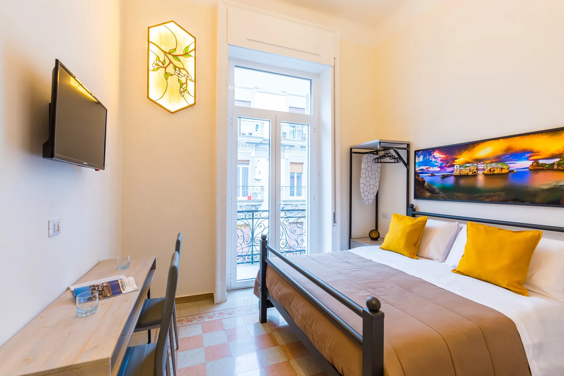 Un dormitorio con una cama, un escritorio y un televisor montado en la pared.