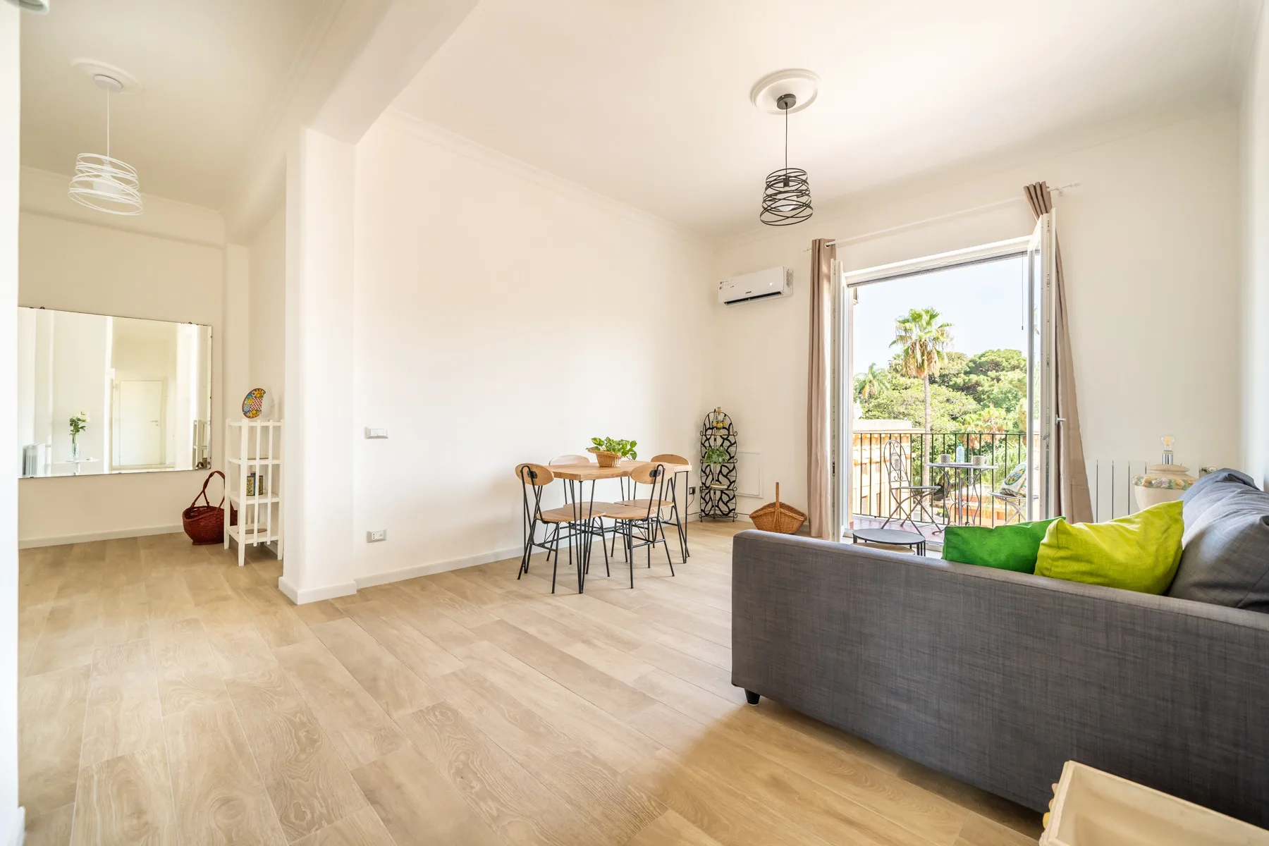 Una luminosa zona de estar y comedor tiene una mesa, asientos y una puerta al balcón.