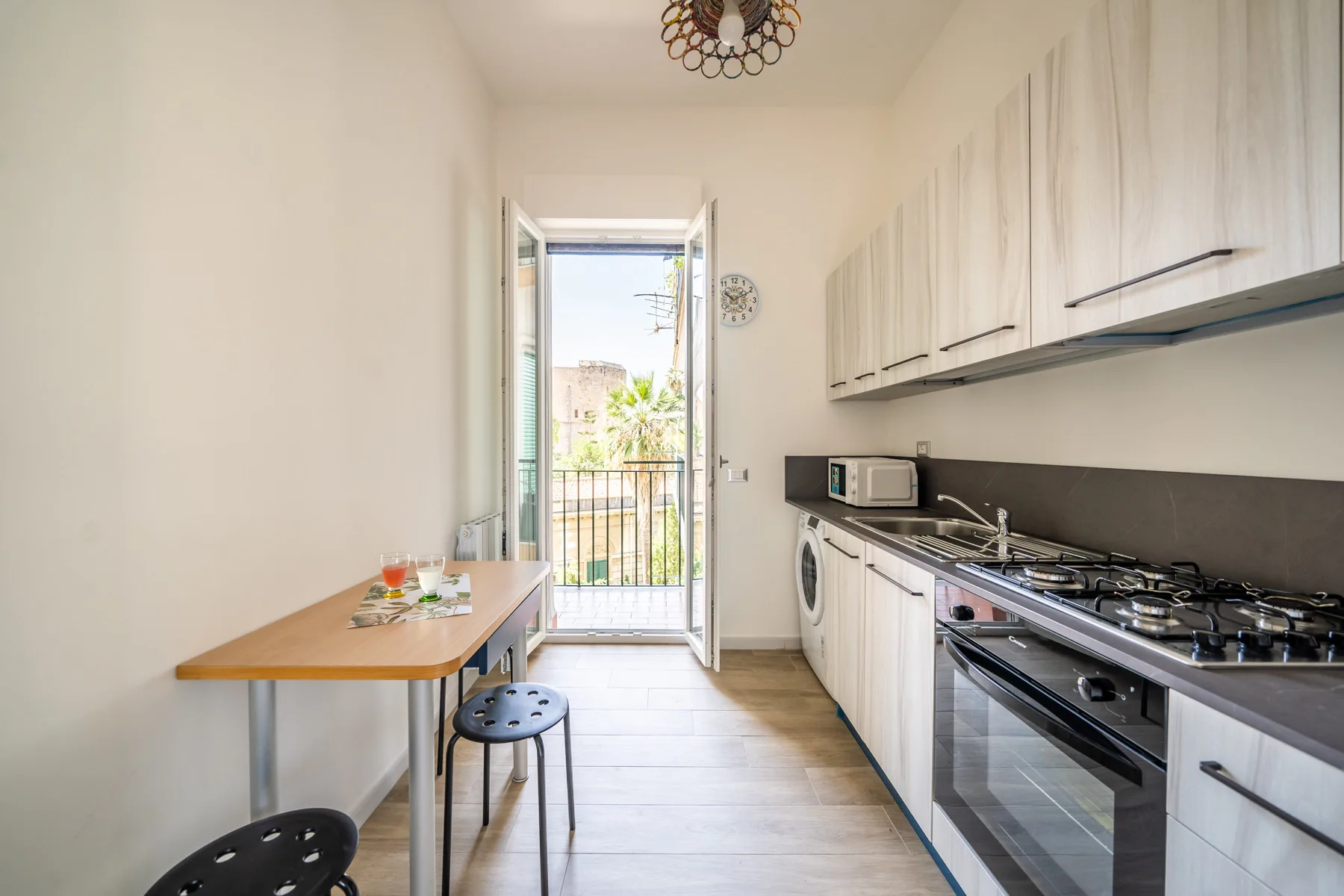 Una cocina luminosa con una mesa junto a una puerta abierta al balcón.