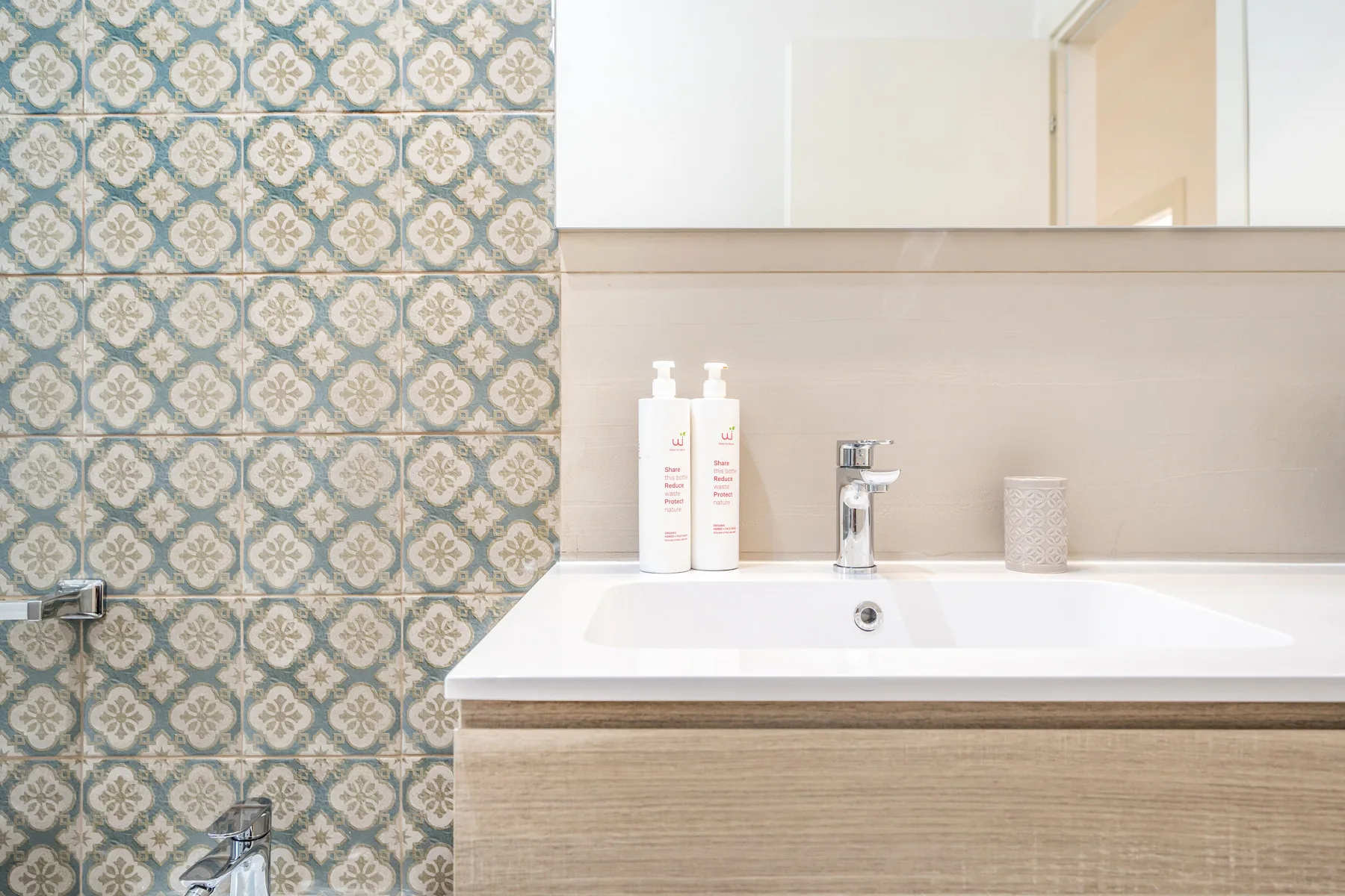 Un tocador de baño con lavabo, grifo y azulejos estampados.