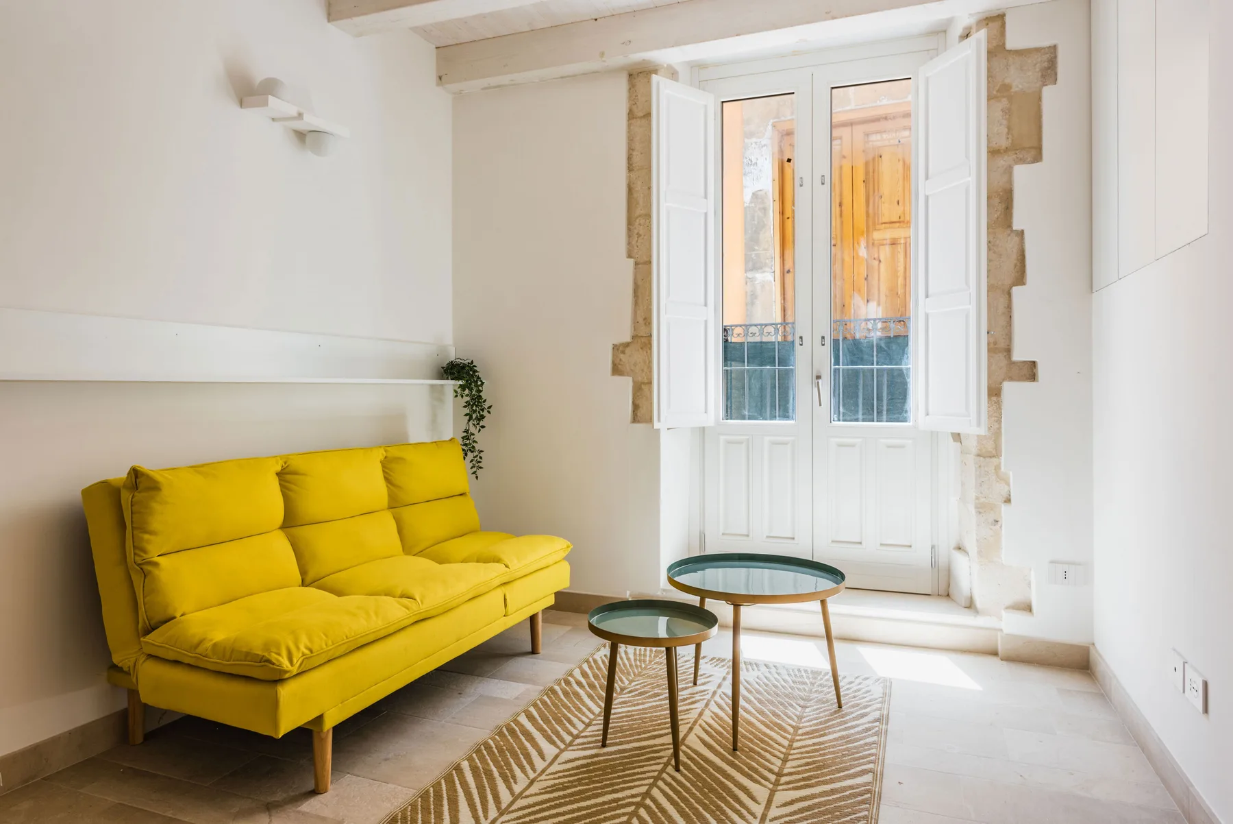 A bright living room with a yellow sofa and an open window.