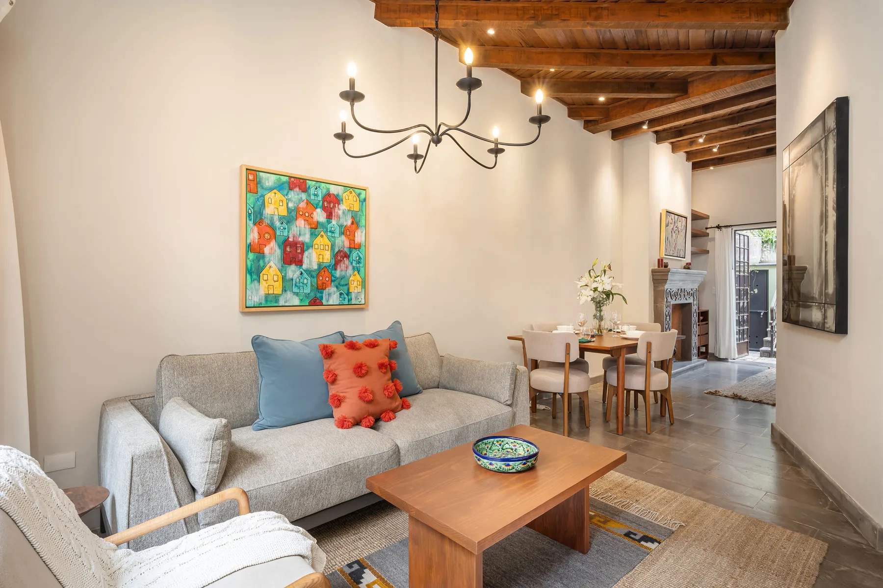 A living and dining area with seating beneath exposed wooden ceiling beams.