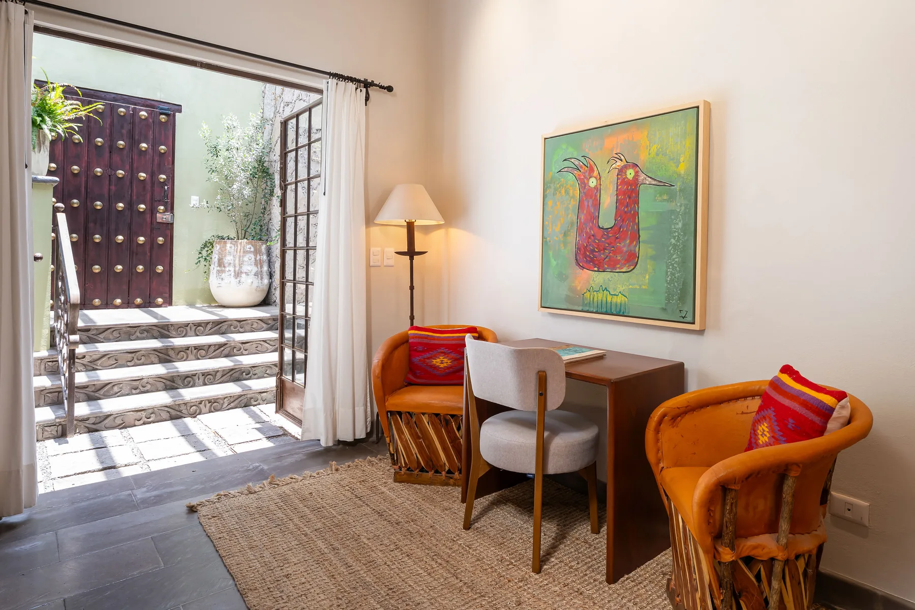 A bright sitting area with orange seating and a desk beside an open patio doorway.