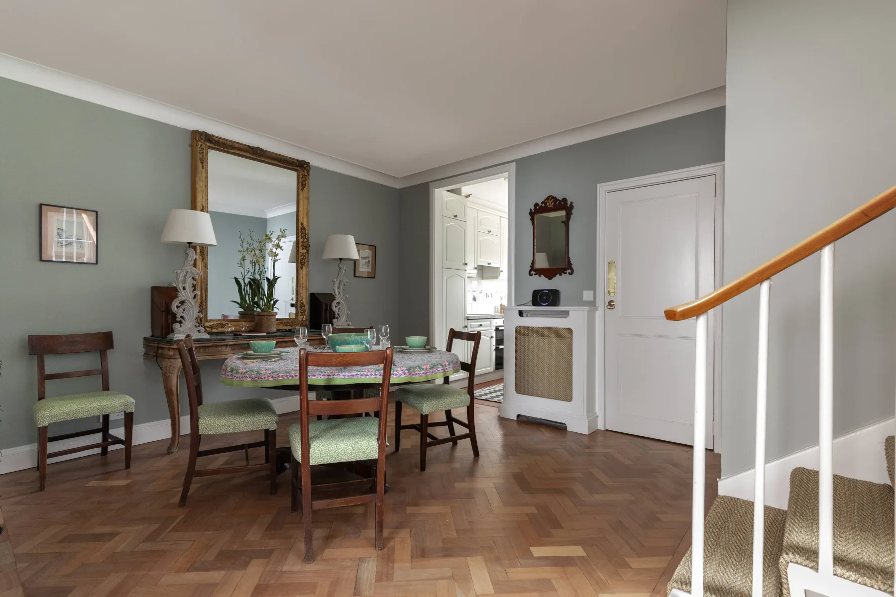 A dining room with a wooden table and chairs beside a bright kitchen.