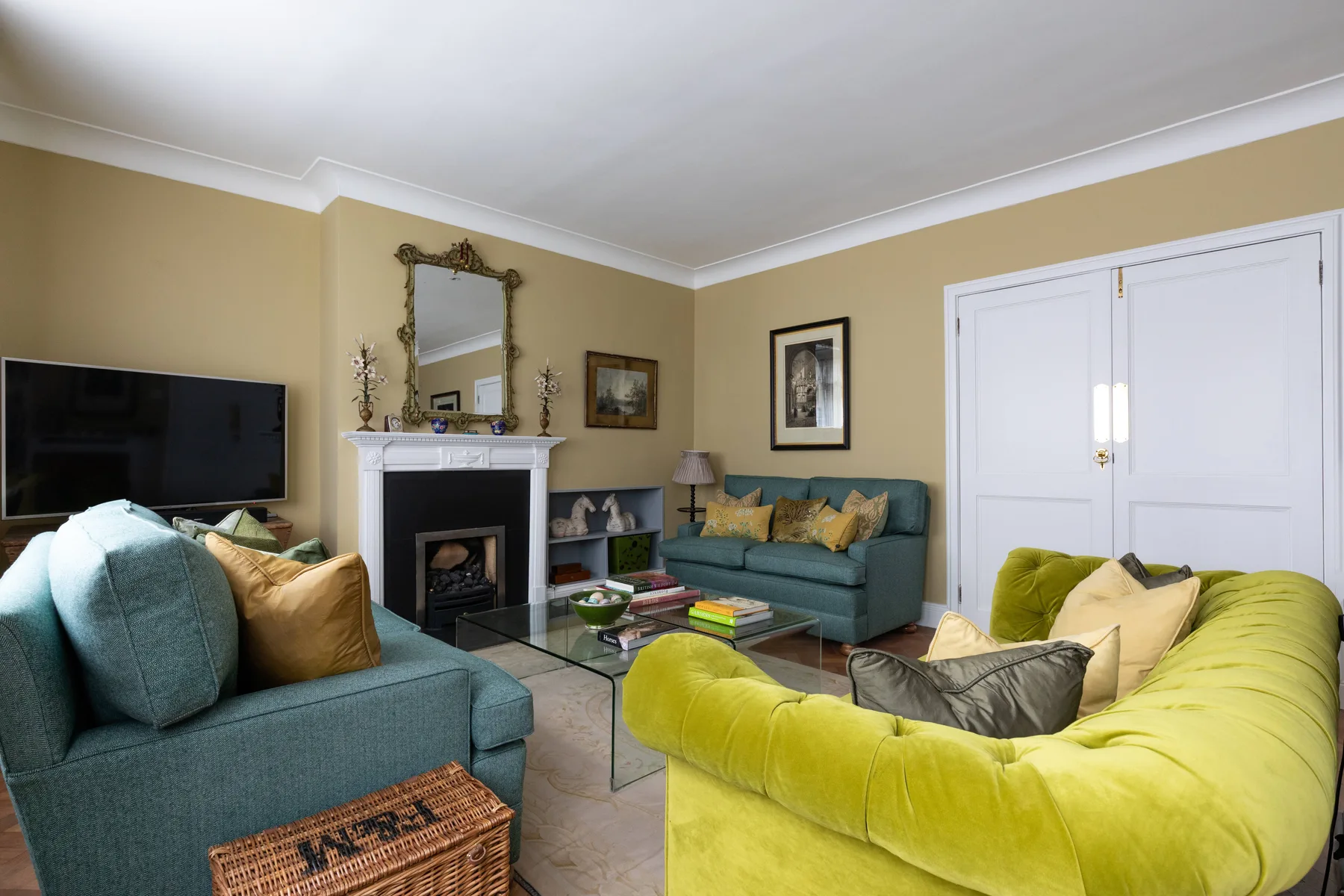 A living room with colorful seating arranged around a fireplace and coffee table.