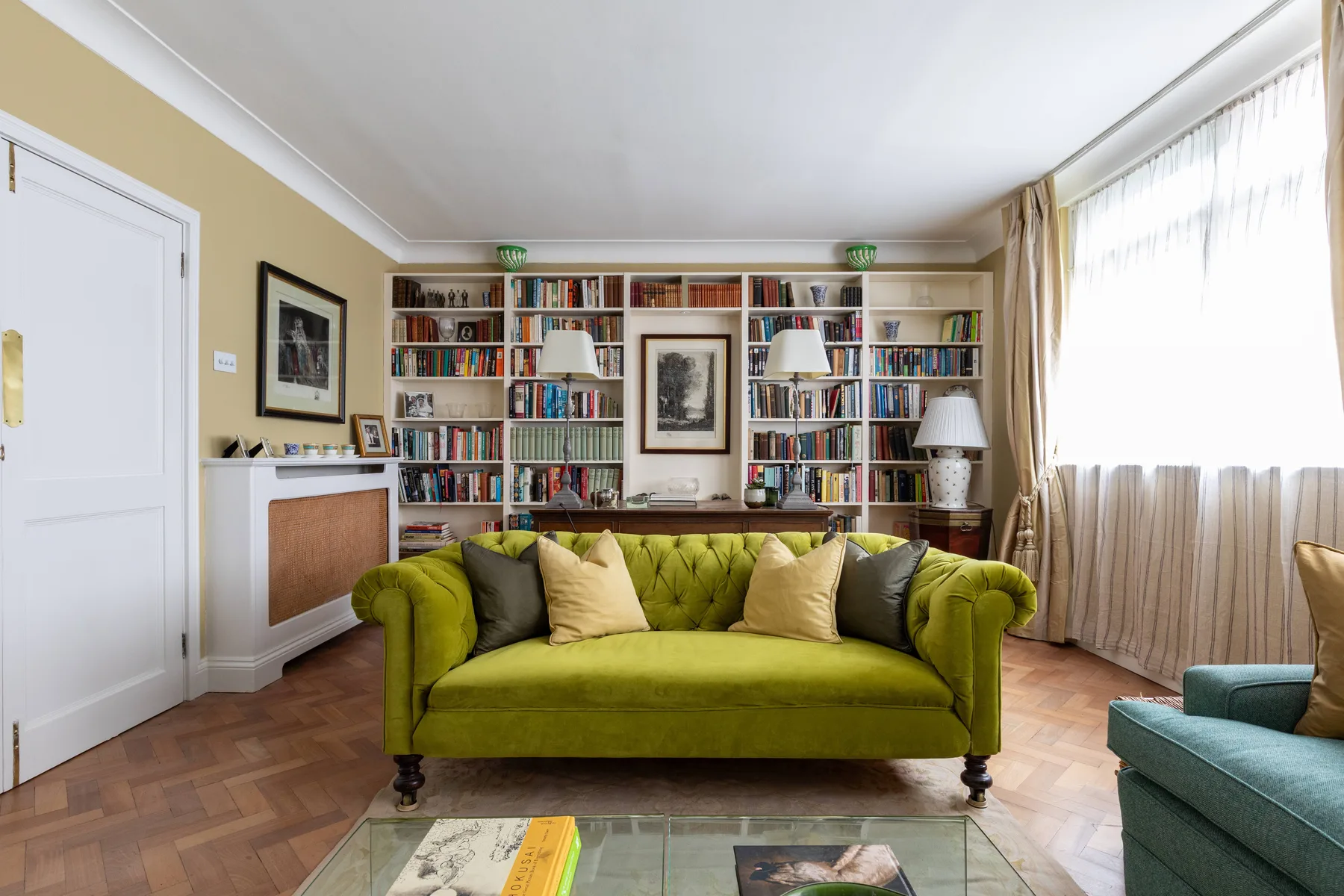 A living room with a green sofa and bookshelves along the back wall.