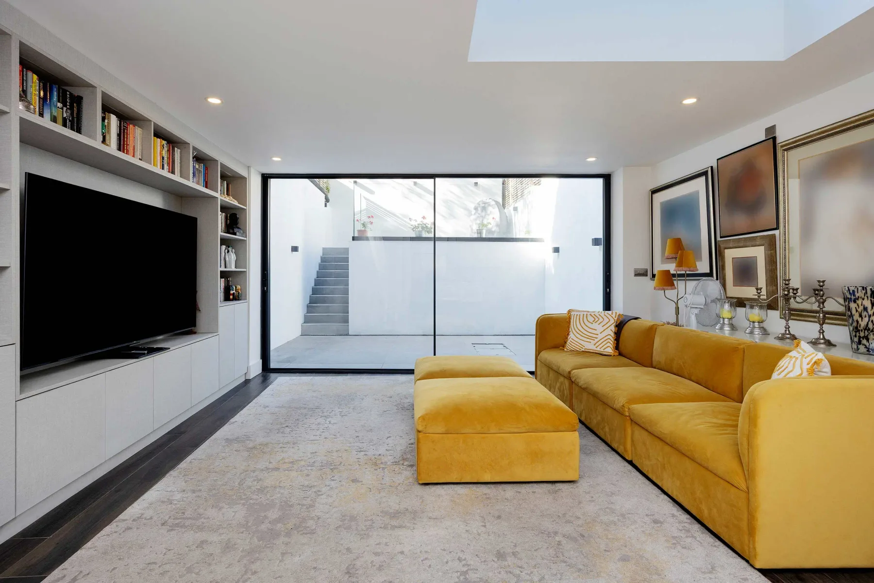 A living room with yellow seating and a large television.
