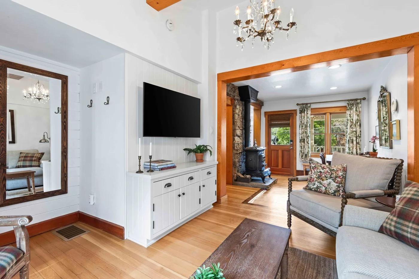 A bright living room with a television, seating, and a wood stove.
