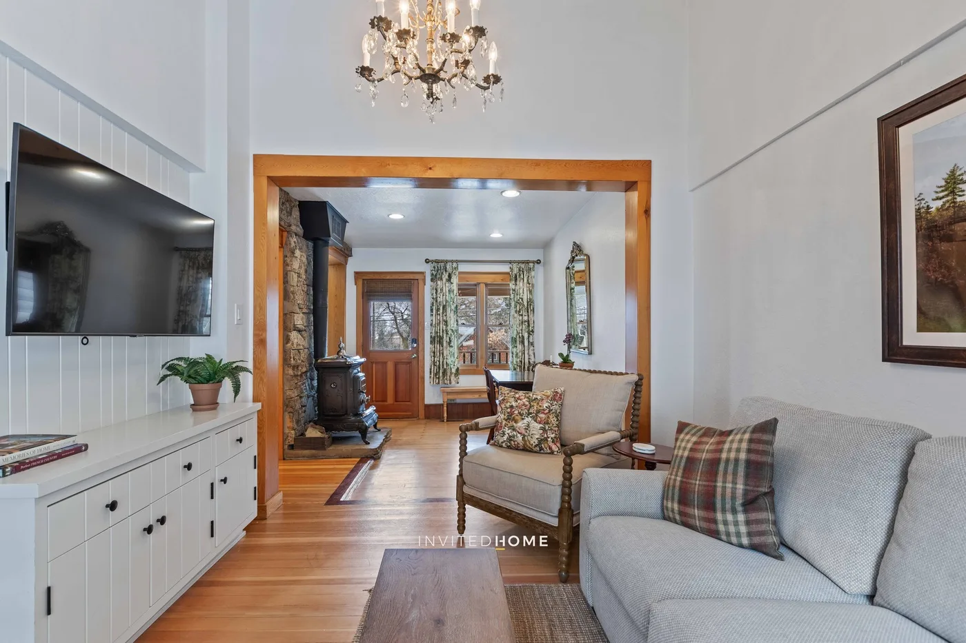 A bright living room with seating, a television, and a wood-burning stove.