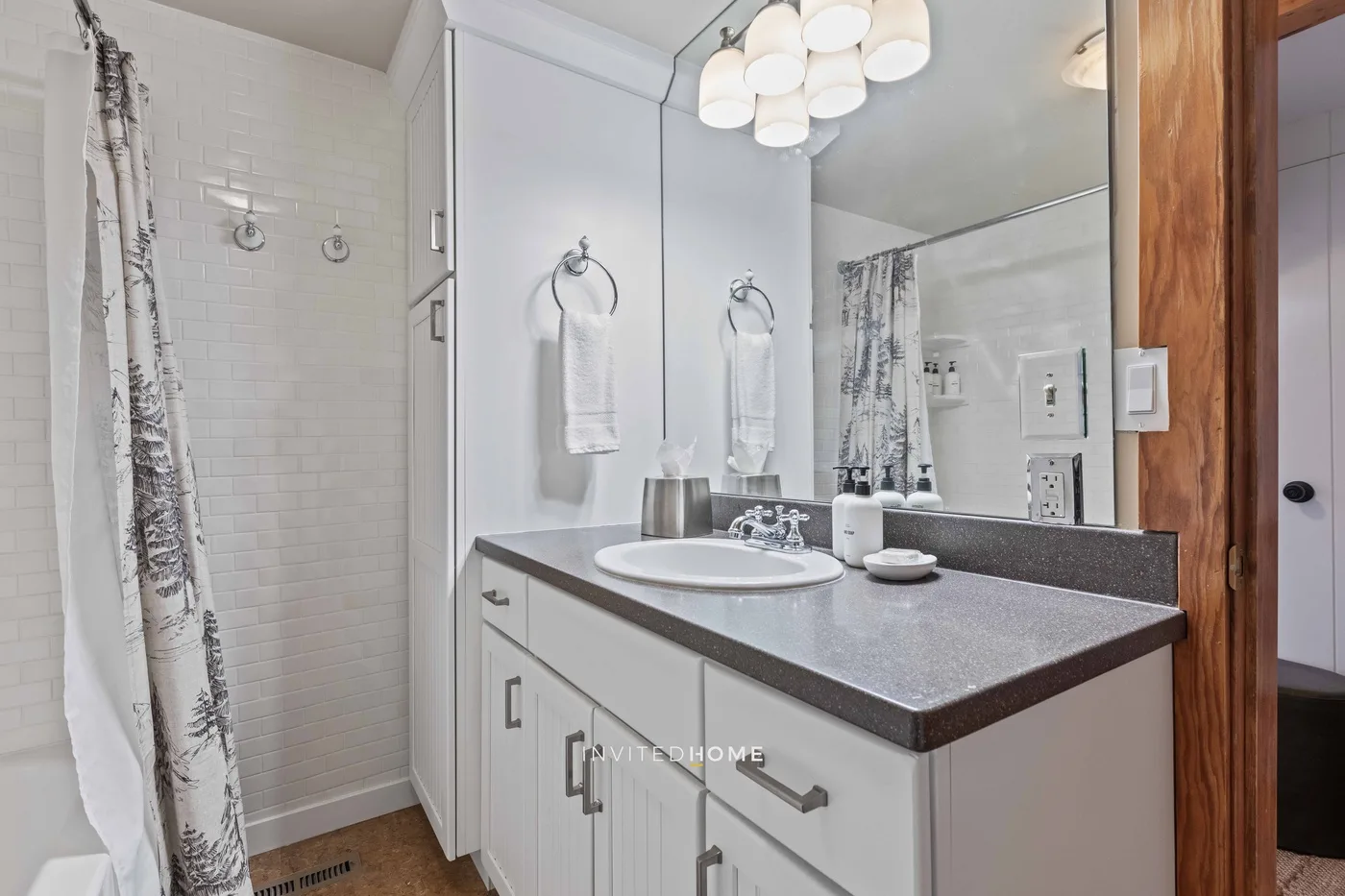 A bright bathroom with a long vanity, mirror, and shower curtain.