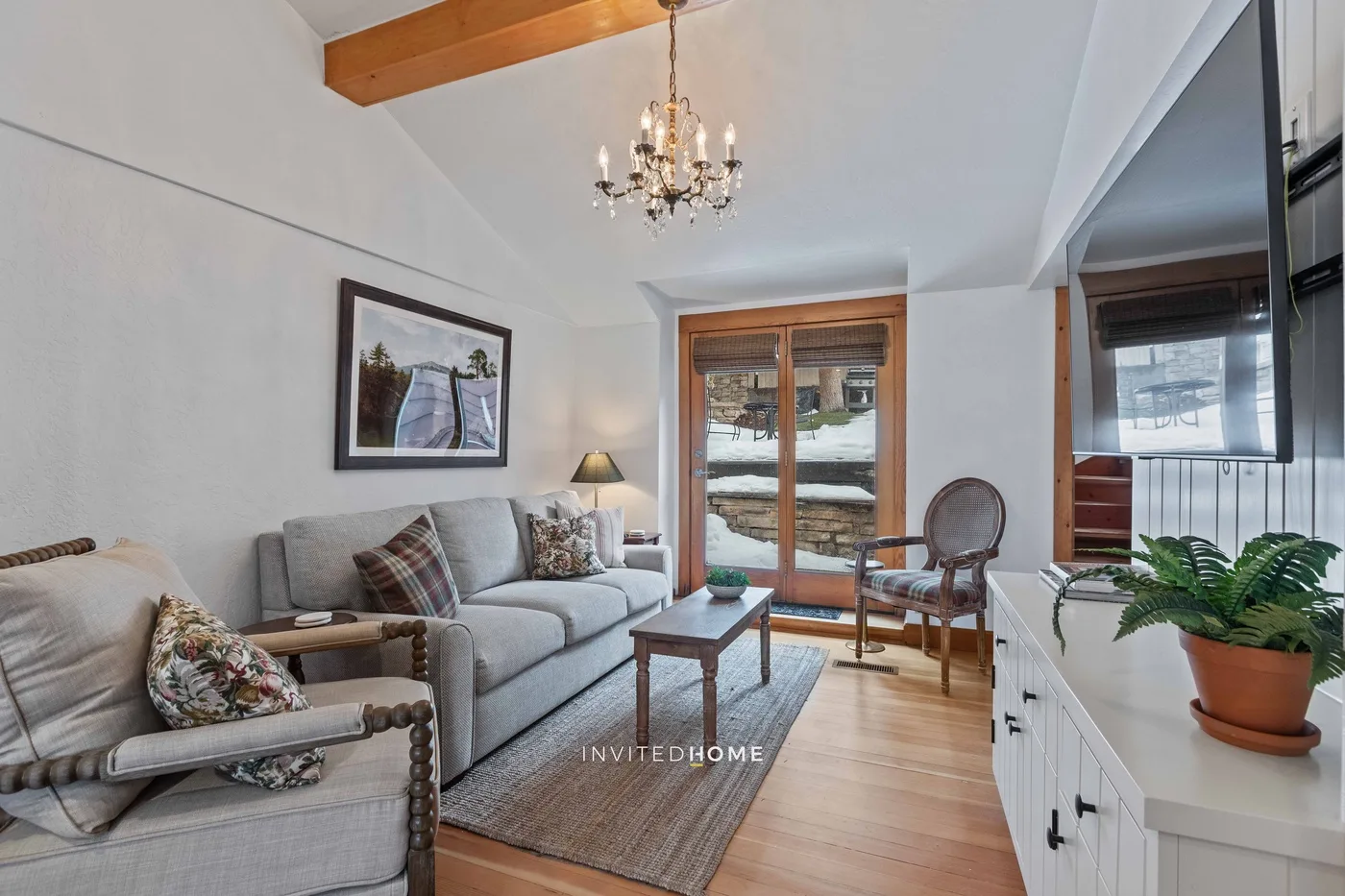 A living room with seating, a coffee table, and glass doors opening onto a snowy view.