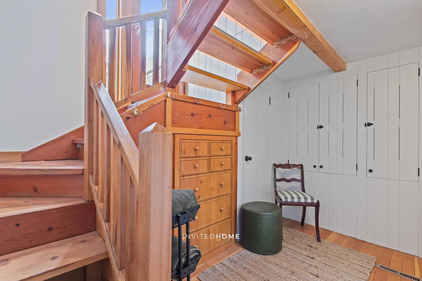 A wooden staircase and loft area with storage cabinets and a small seating space.
