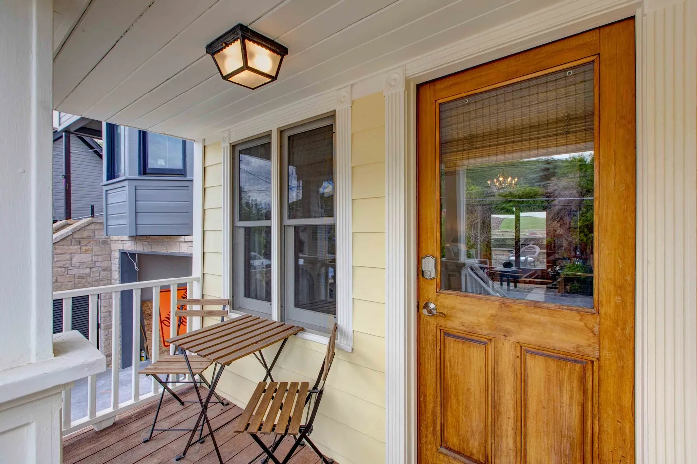 A covered porch with wooden seating beside a glazed entry door.