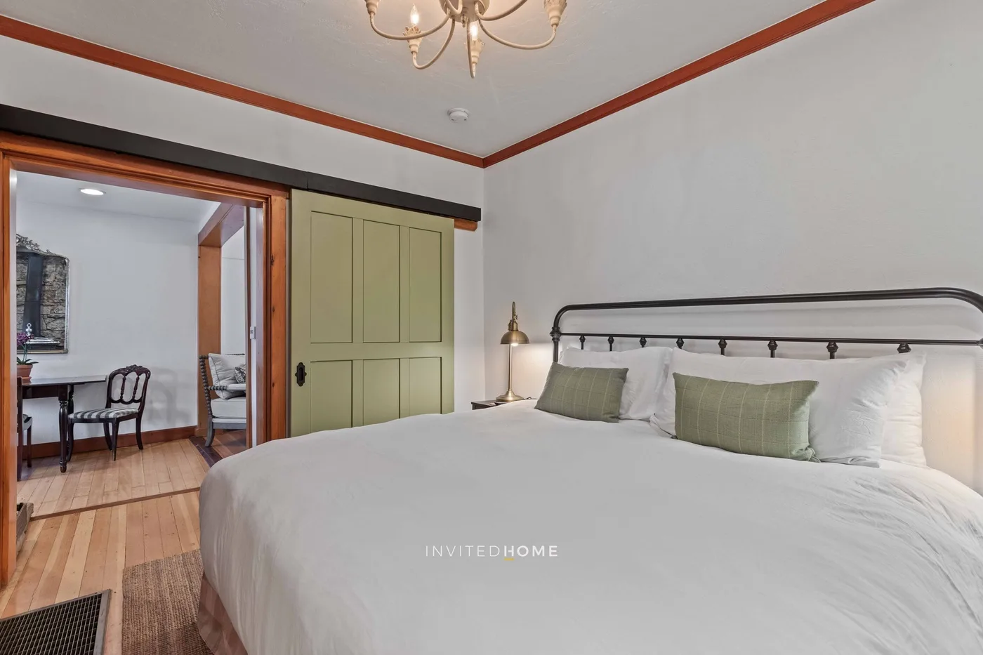 A bedroom with a large bed and an open doorway to a sitting area.