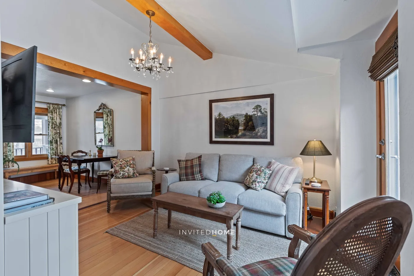 A living room with seating around a coffee table and a dining area beyond.