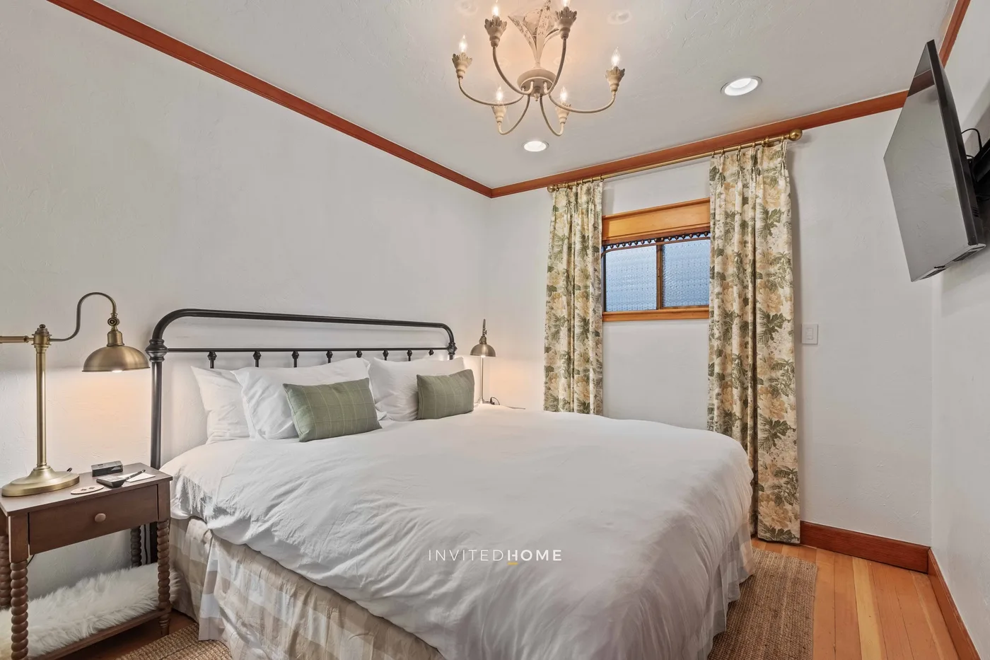 A bedroom with a large bed, bedside lamps, and a curtained window.