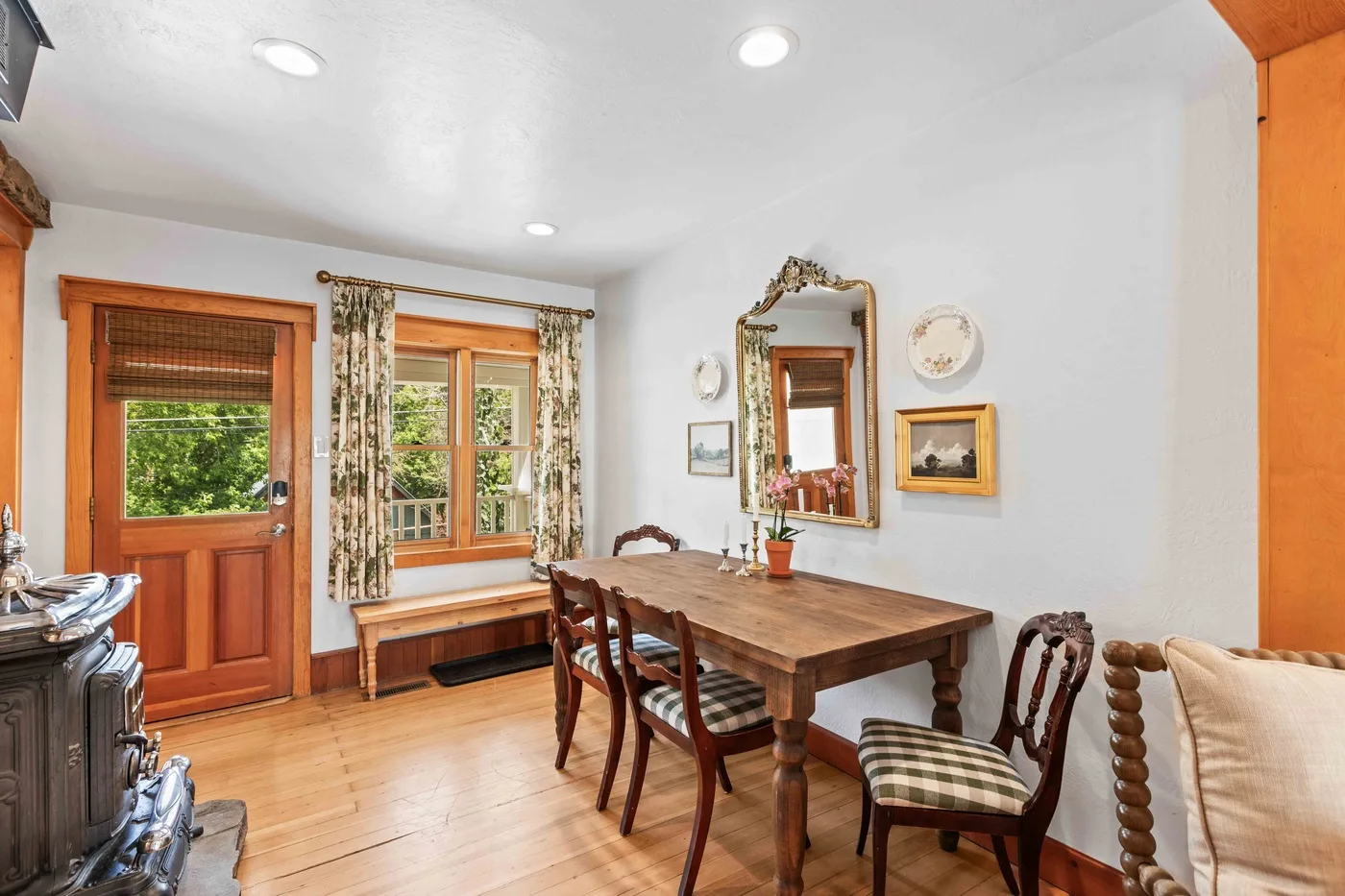 A dining room with a wooden table and chairs beside a door and windows.