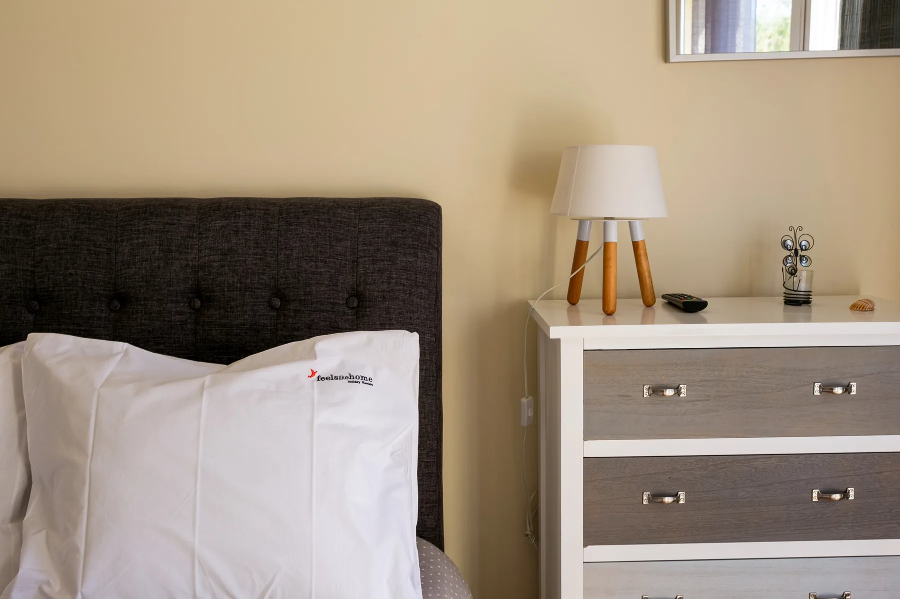 A bedroom with a bed beside a dresser and table lamp.