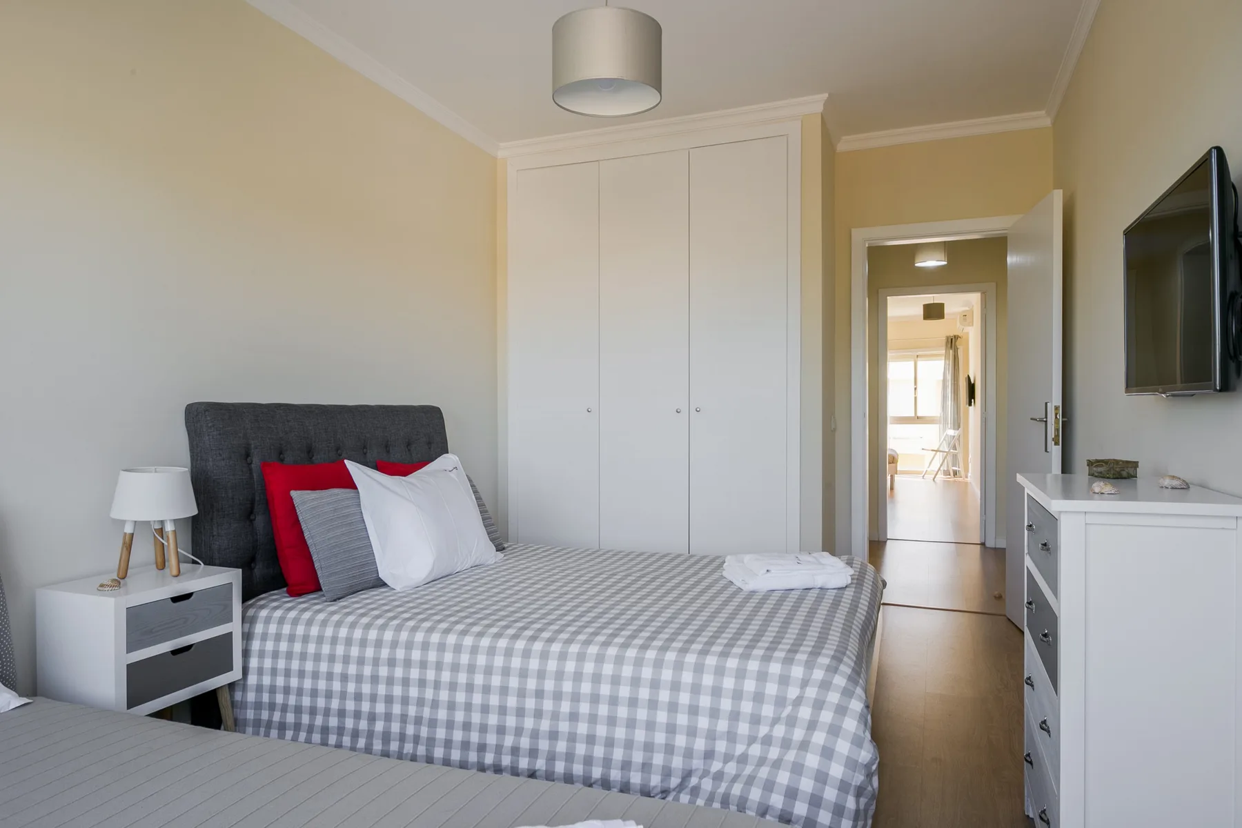 A bedroom with a made bed, bedside table, and built-in wardrobe.