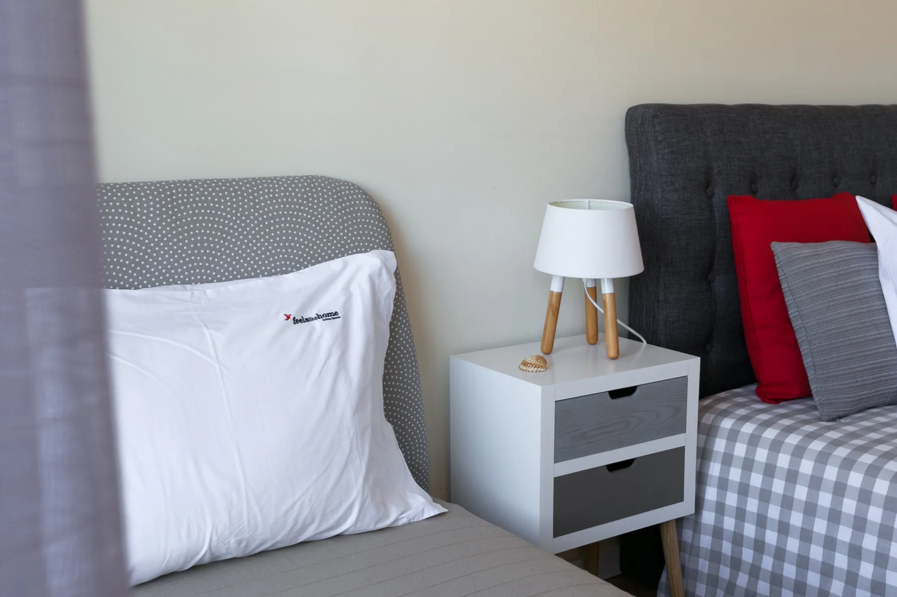 A bedroom with two beds and a bedside table with a lamp.