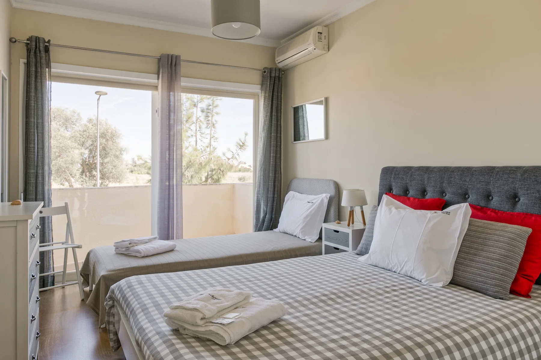 A bedroom with two beds and large windows opening onto a balcony.
