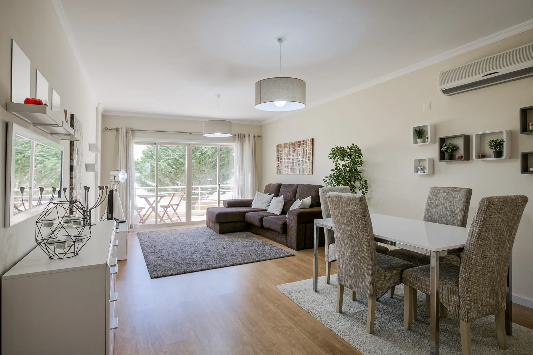 A bright living and dining area opens onto a balcony through large glass doors.