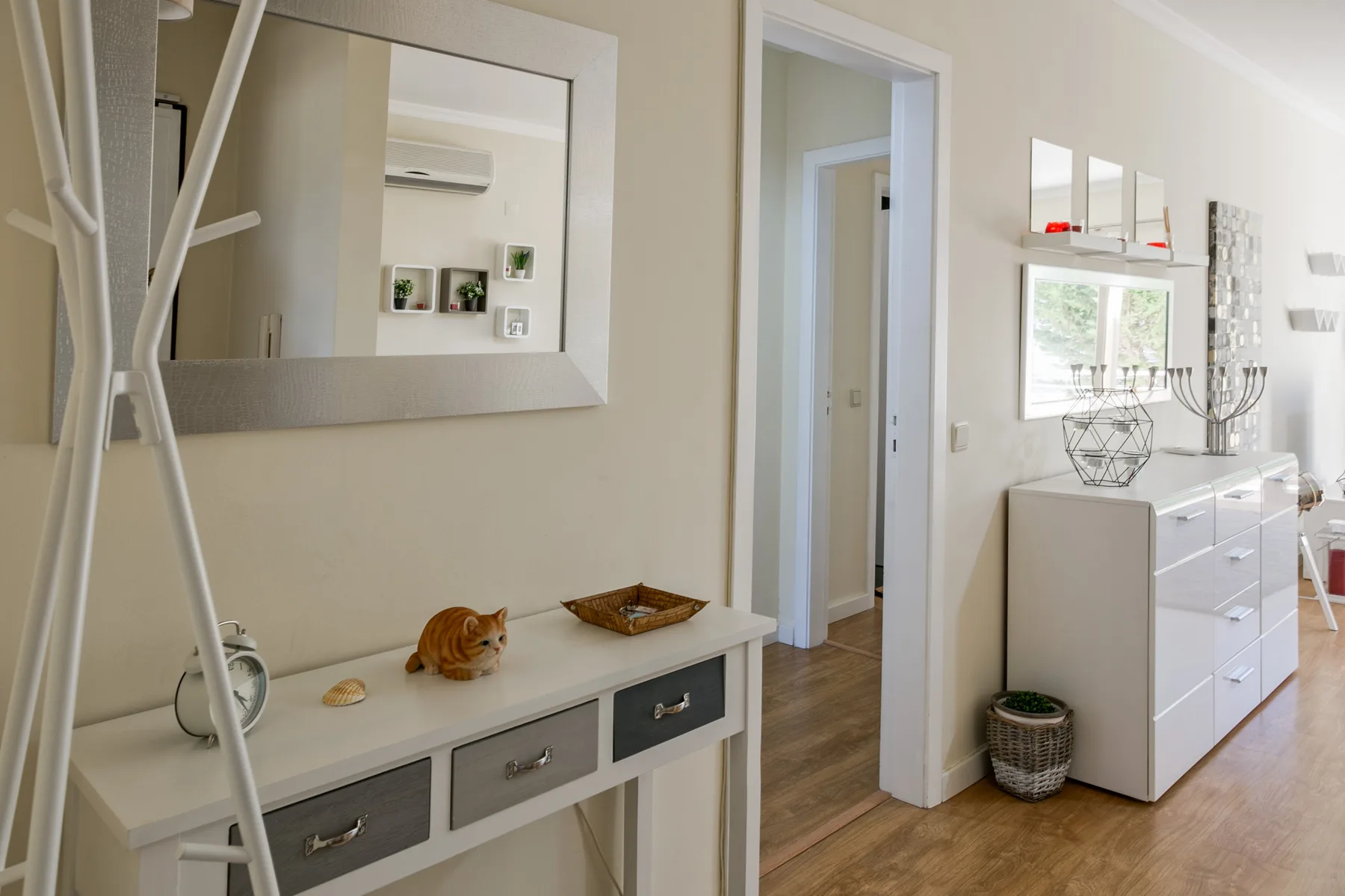 A bright entryway with a console table, mirror, and a cat.
