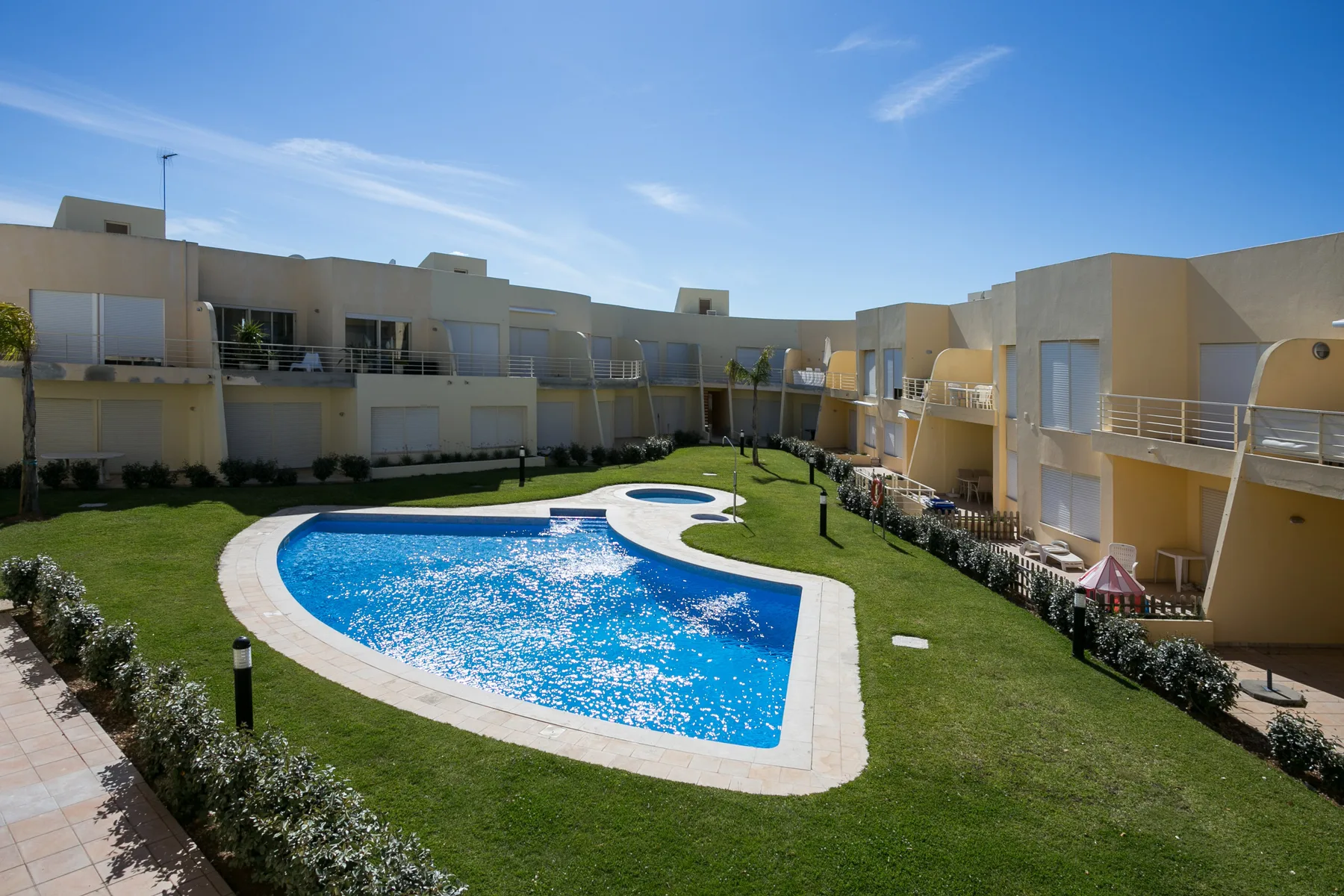 A swimming pool sits in a landscaped courtyard surrounded by apartment buildings.