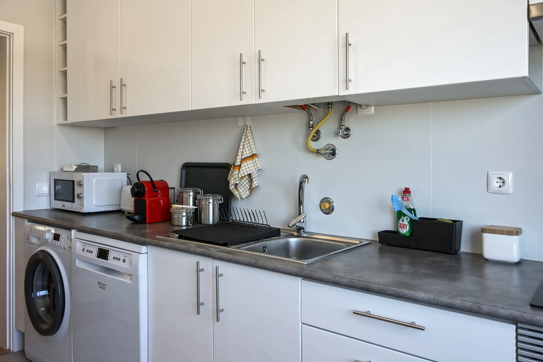 A compact kitchen with a sink, countertop appliances, and a washing machine.