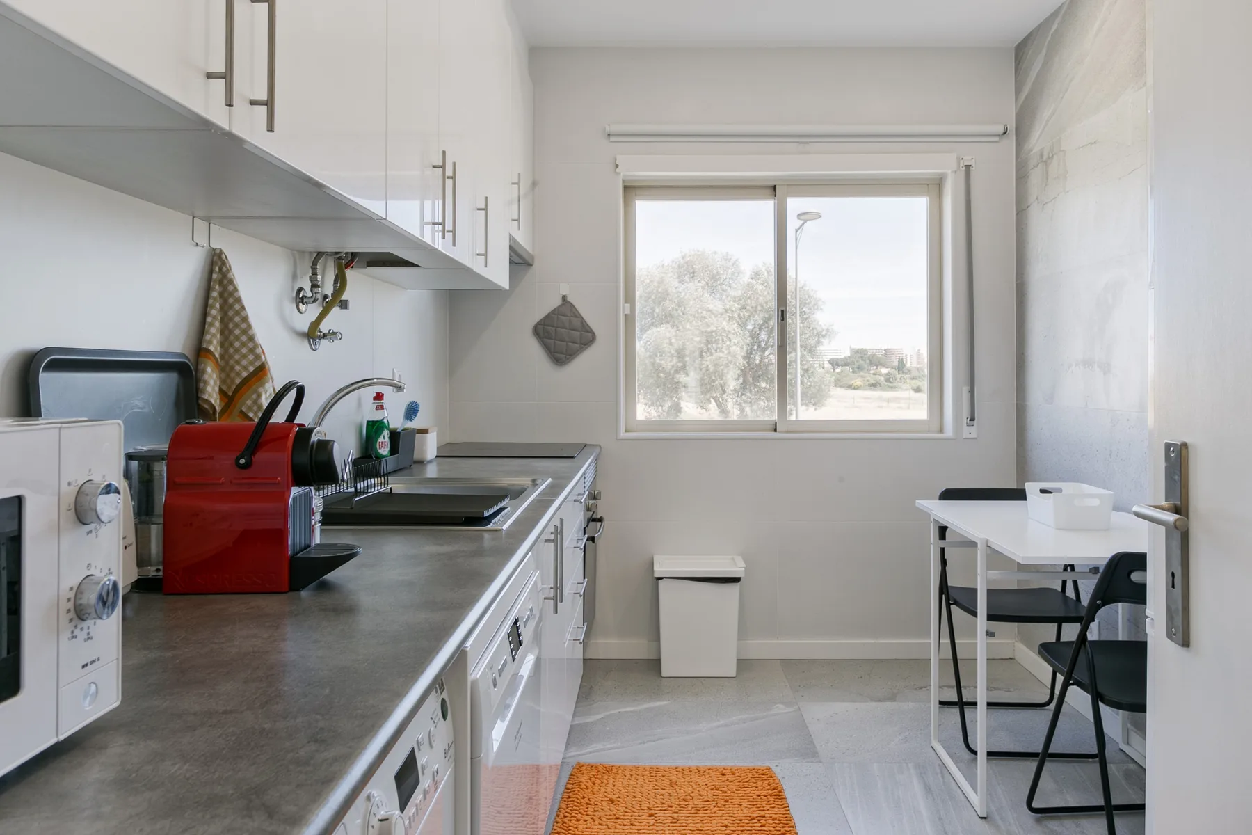 A bright kitchen with a counter, cabinets, and a small dining table by the window.