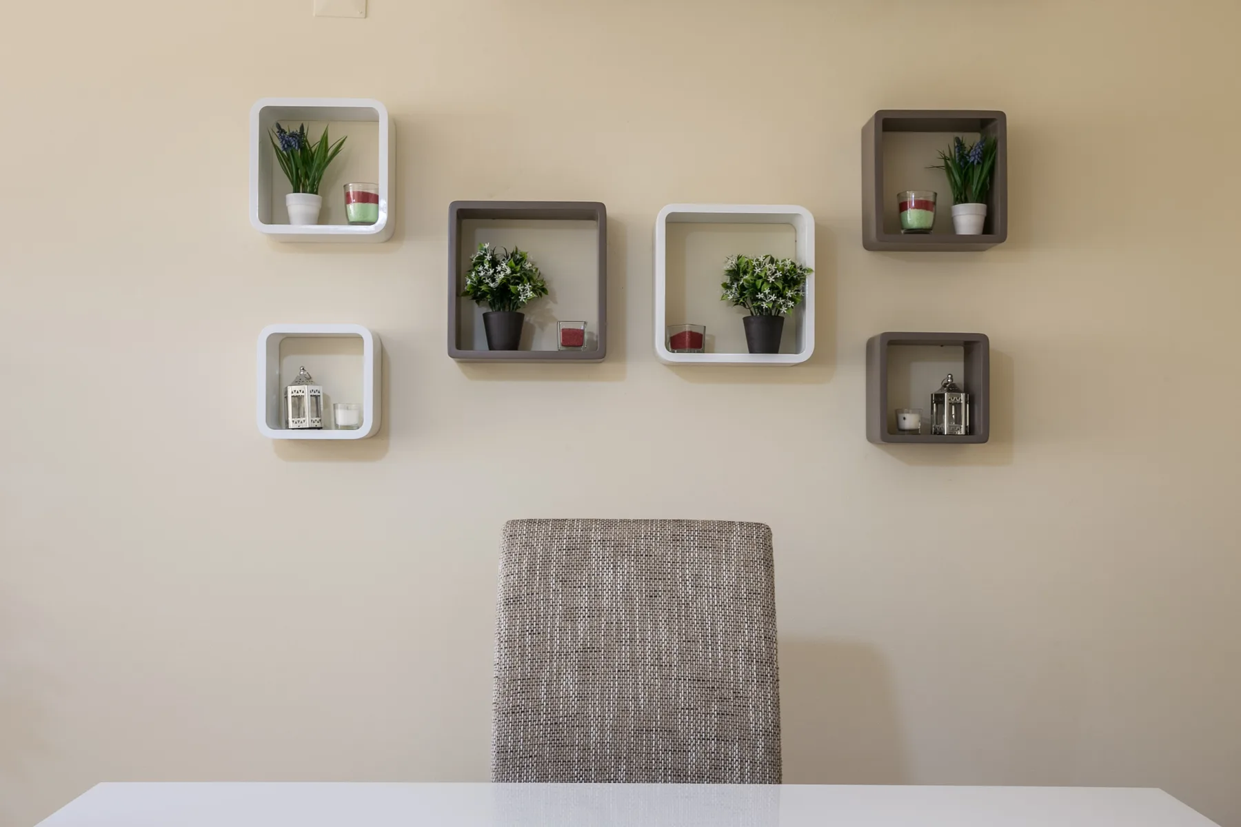 A dining area with a fabric-covered chair and decorative wall shelves.