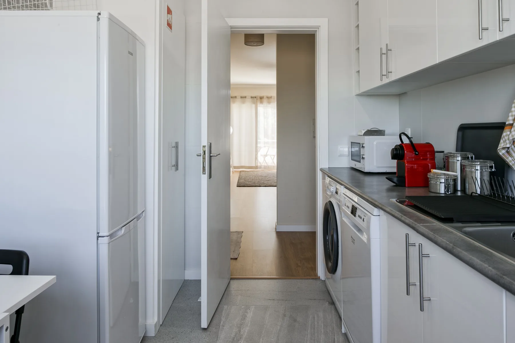 A compact kitchen with white cabinets, appliances, and a counter.