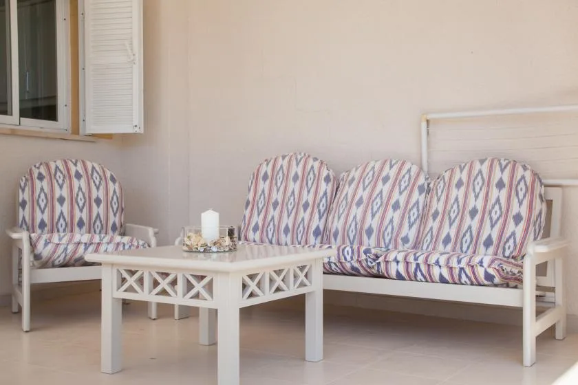 Una zona de estar en un patio cubierto con cojines estampados y una mesa baja.