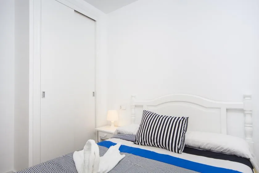 Un dormitorio con una cama, almohadas a rayas y una puerta blanca de armario corrediza.
