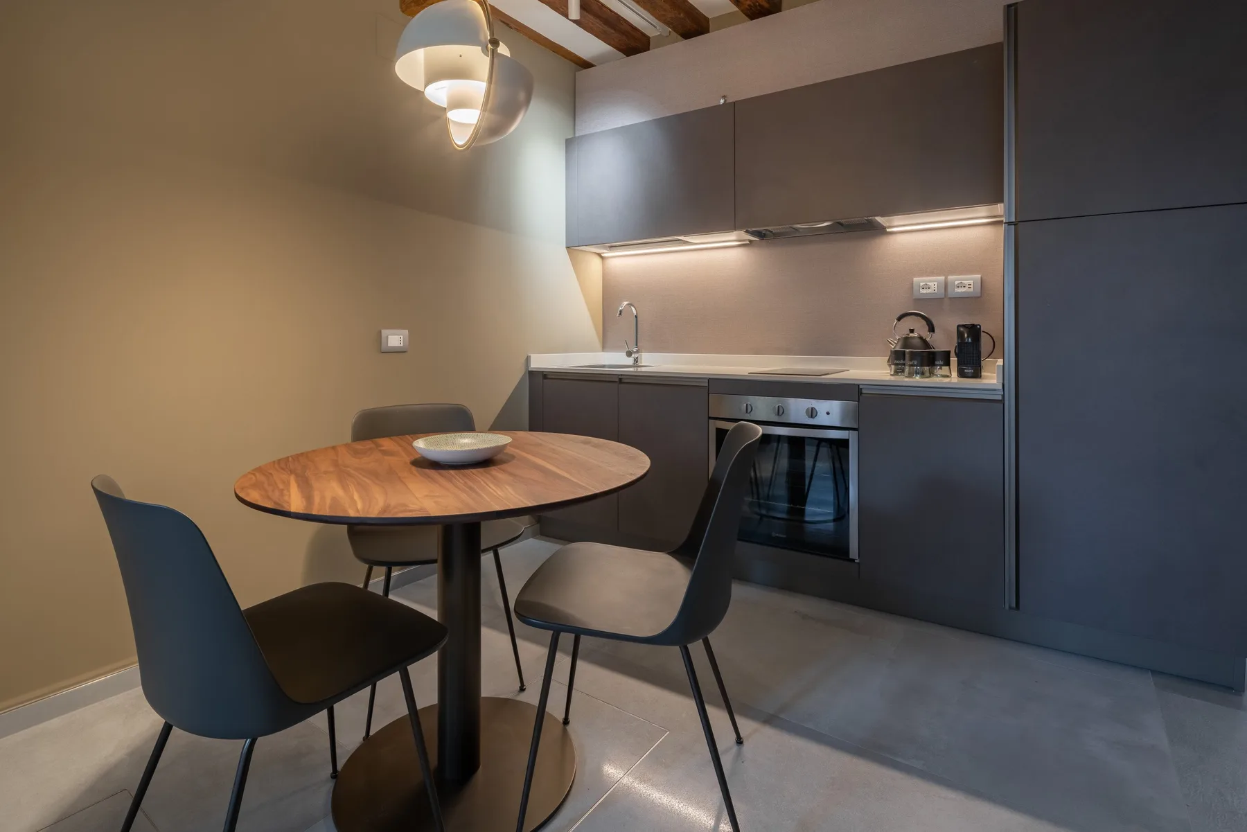 Comedor con una mesa redonda y asientos junto a una cocina compacta.