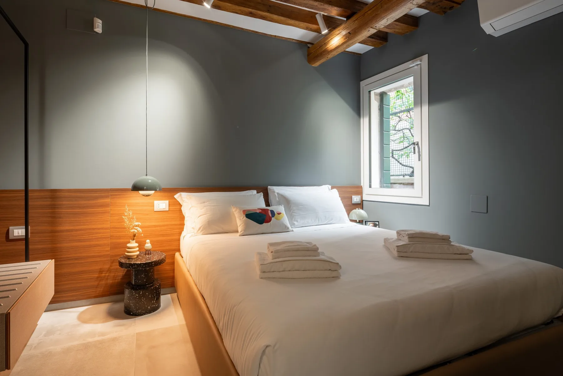 Un dormitorio con una cama grande, paredes revestidas de madera y una ventana.