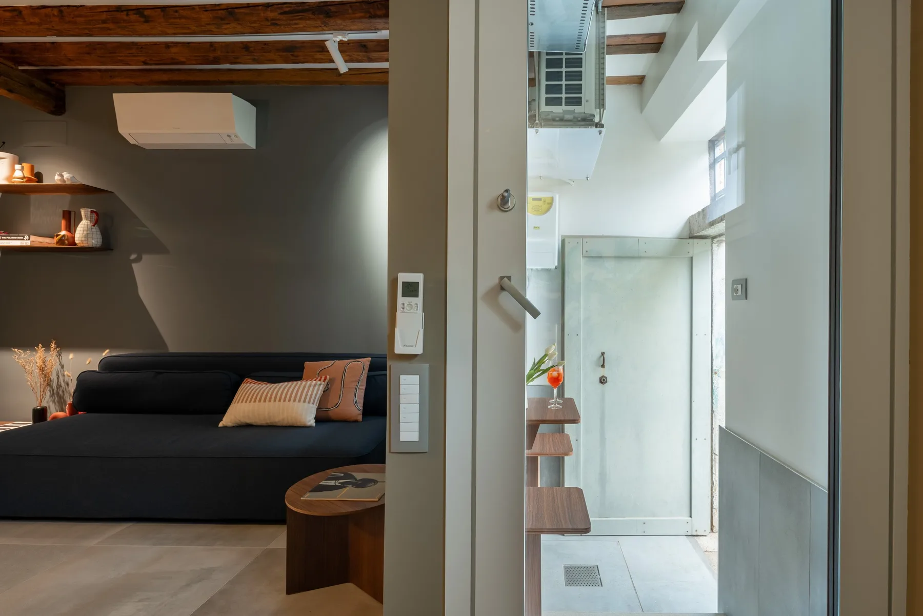 Un dormitorio moderno con una cama oscura junto a un baño luminoso.