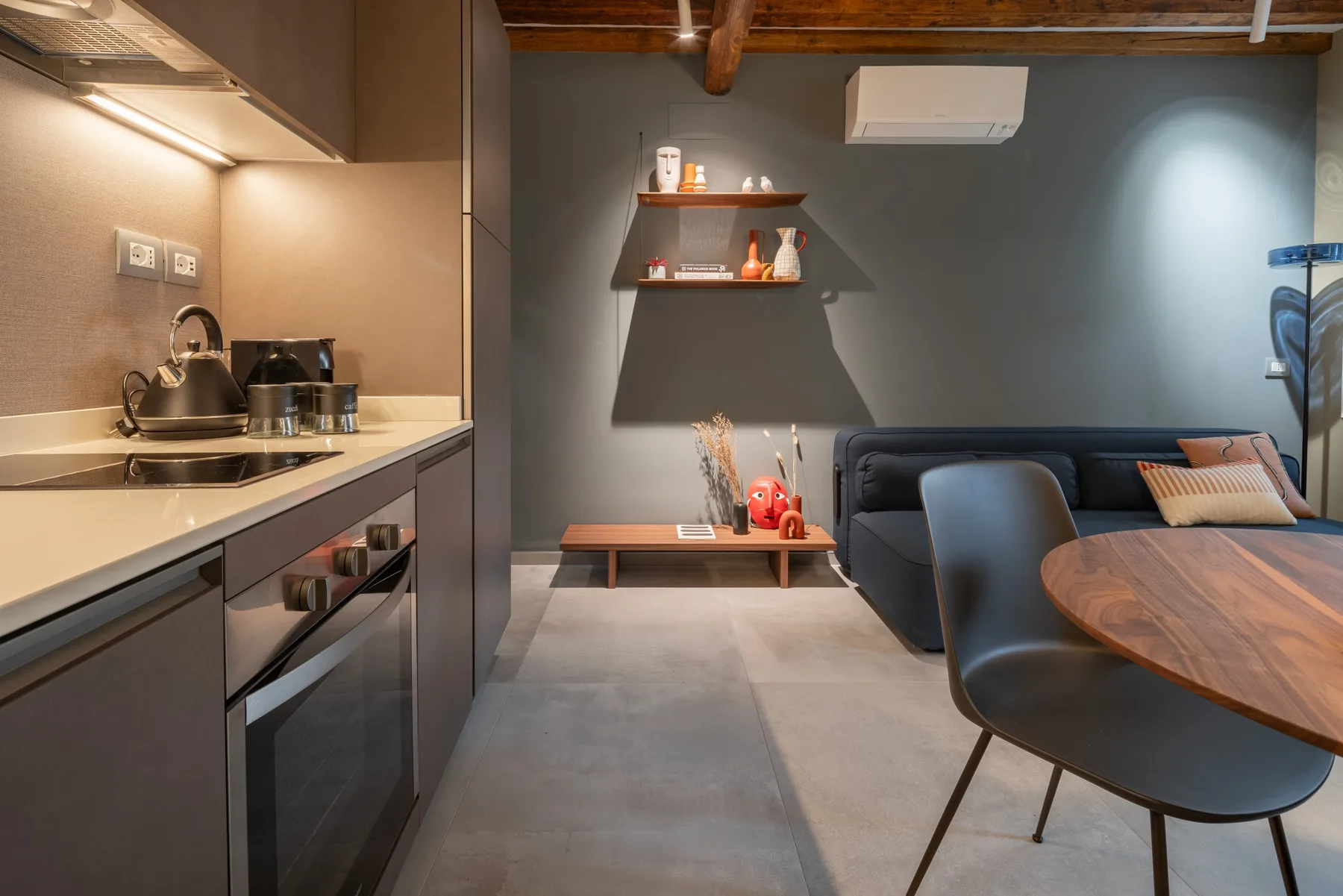 Una sala de estar moderna con cocina pequeña, asientos y una mesa de comedor.