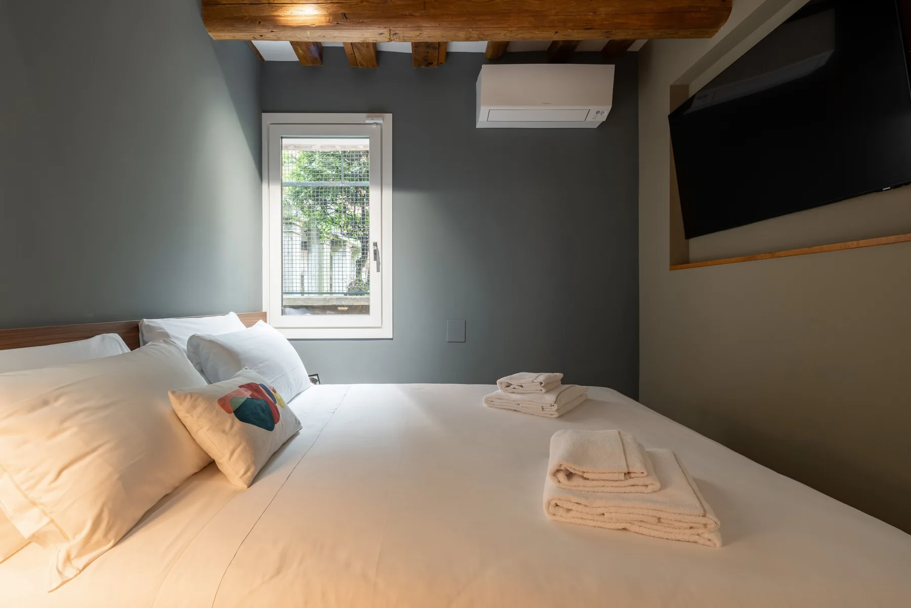 Un dormitorio con una cama bien hecha y una ventana.