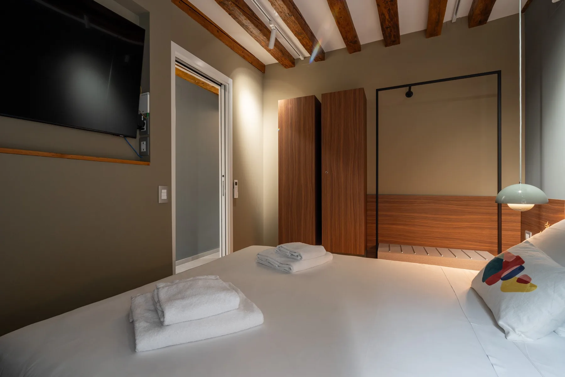 Un dormitorio con una cama, toallas dobladas y vigas de madera en el techo.