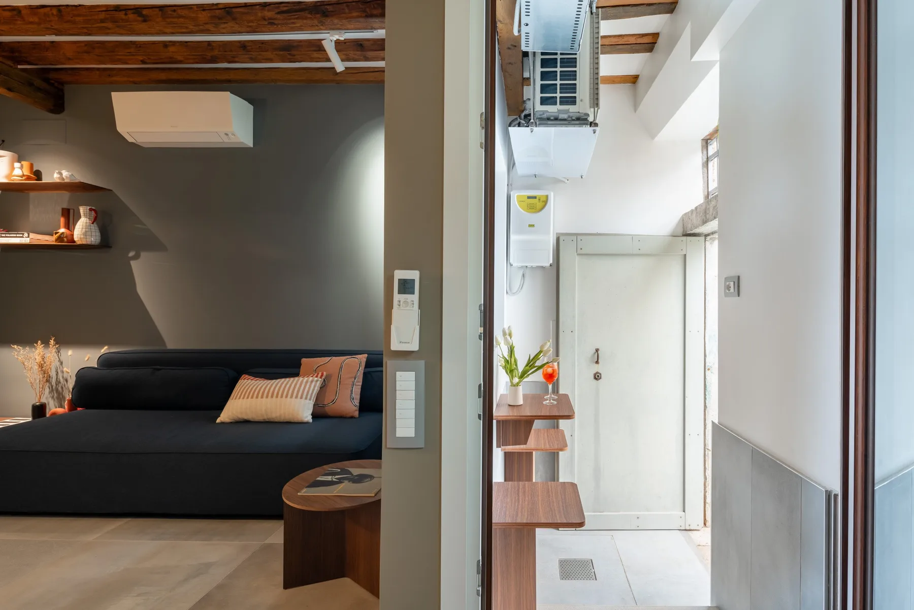 Una sala de estar con asientos oscuros y vigas de madera en el techo.