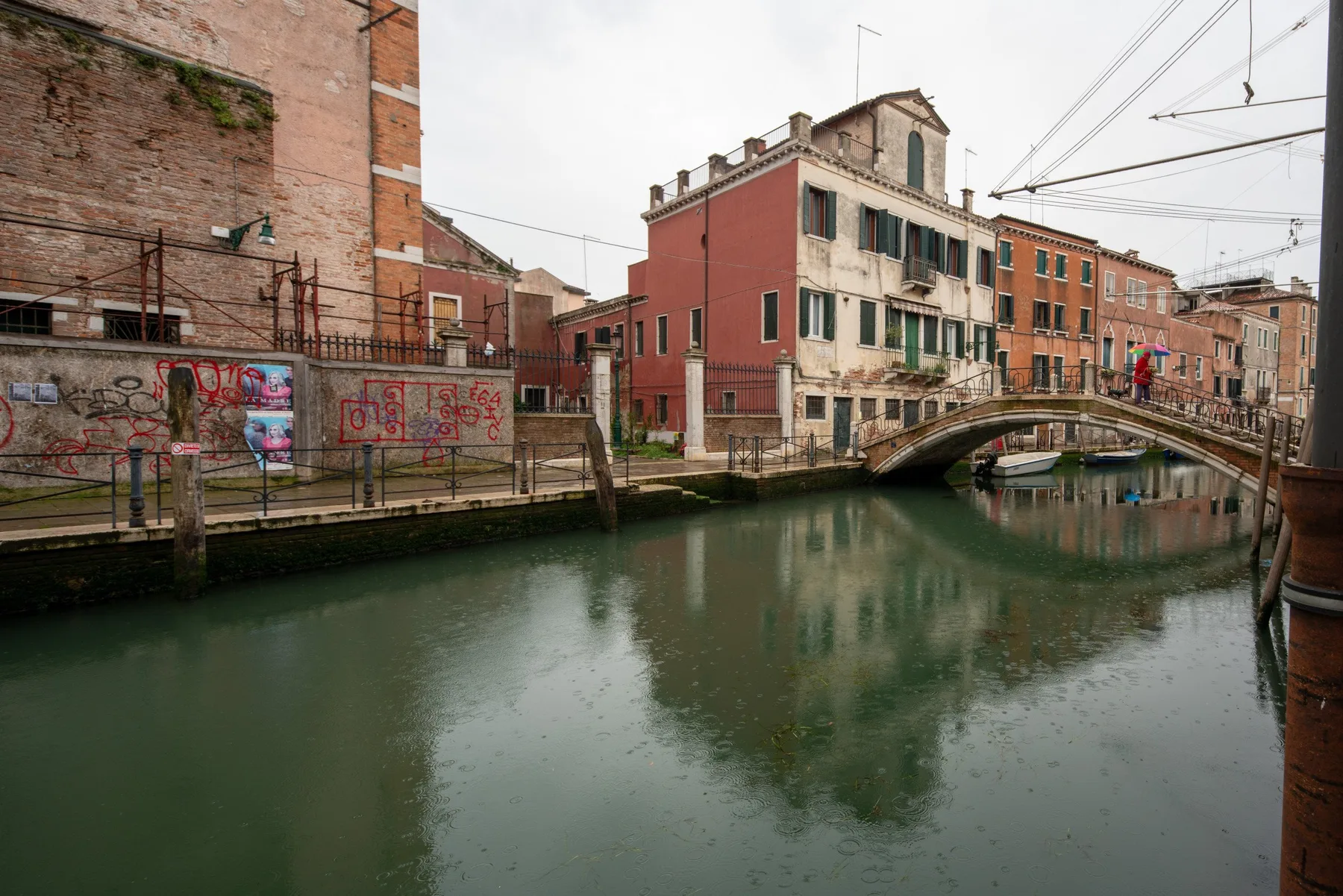 Un canal pasa bajo un pequeño puente peatonal arqueado, entre edificios muy próximos.