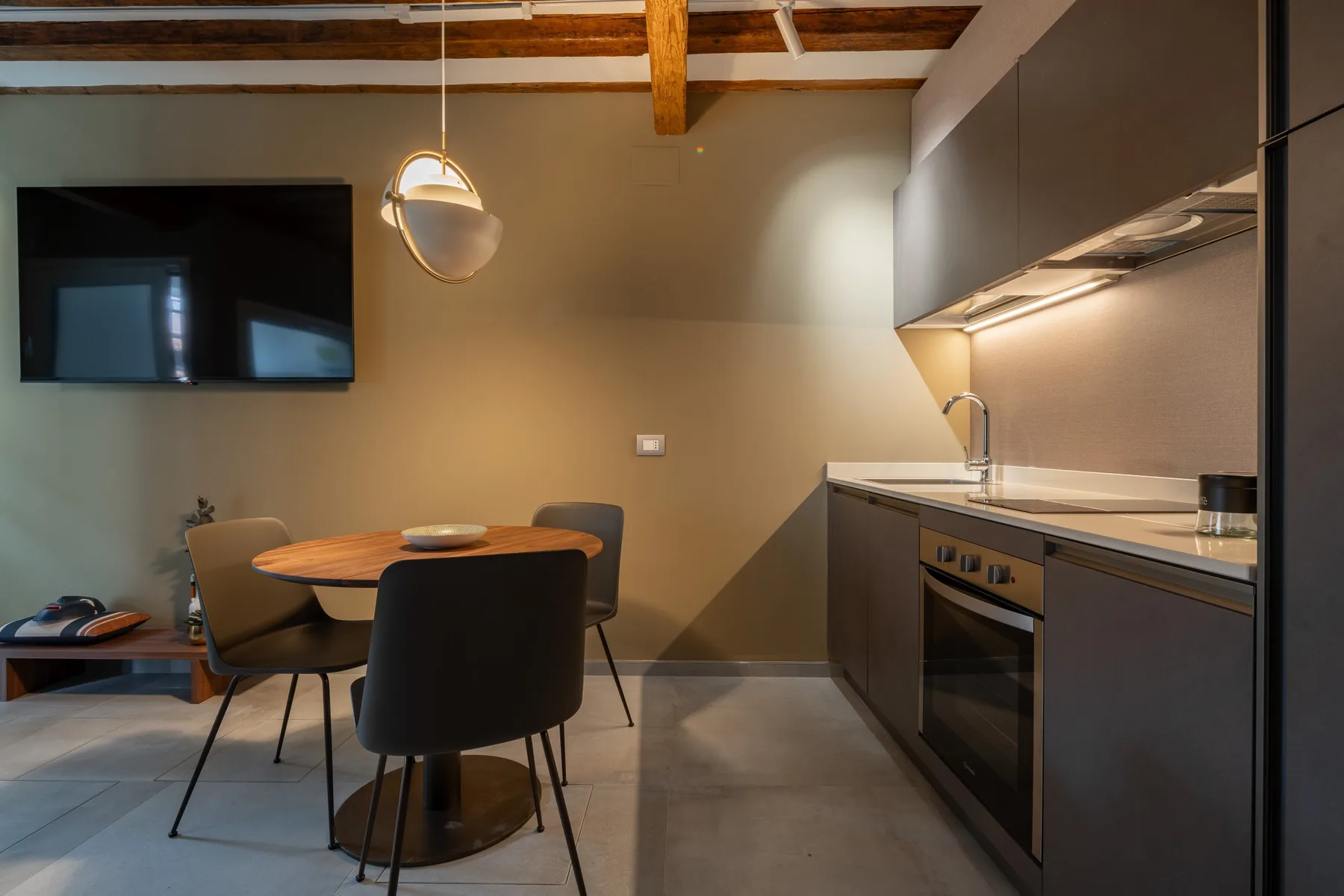 Comedor junto a una cocina moderna, con una mesa y una lámpara colgante.