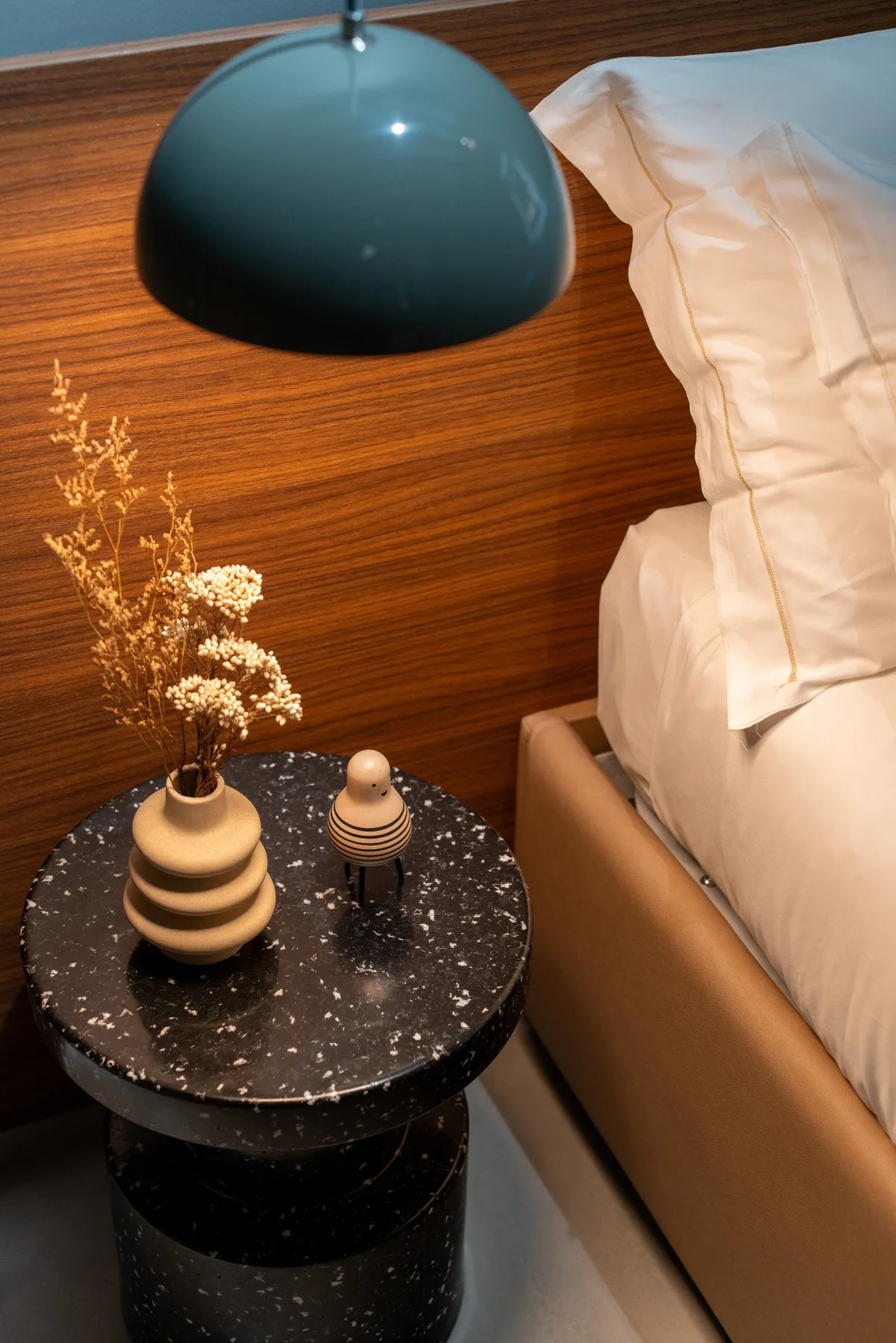Una mesa junto a la cama sostiene objetos decorativos en un dormitorio.