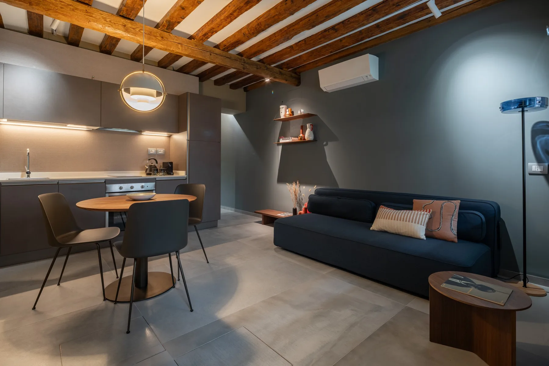 Una sala de estar y cocina de concepto abierto con mesa de comedor y asientos oscuros.