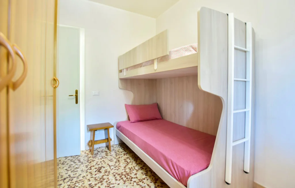 Un dormitorio compacto con una cama rosa integrada en una estructura de madera.