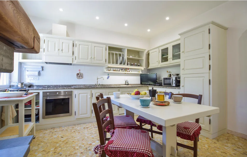 A bright kitchen with white cabinetry and a dining table.